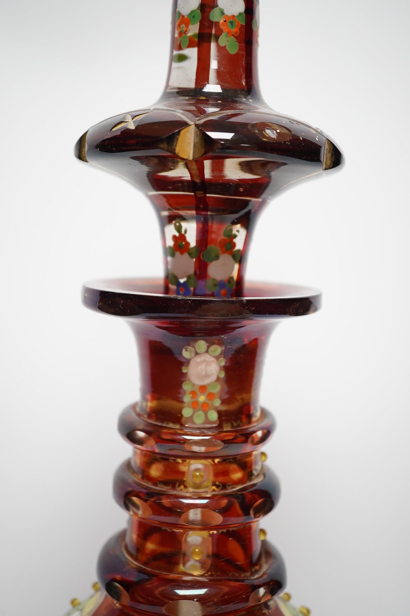 An early 20th century Bohemian overlaid and painted ruby glass decanter, 51cm. Condition - fair